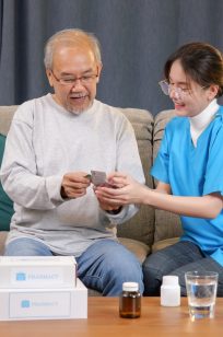 Young doctor examining senior patient at home visit, Senior man consulting medicine with pharmacist, Caregiver nurse taking care of elderly grandfather sitting on sofa at home, Medical service concept