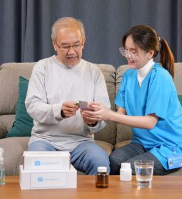 Young doctor examining senior patient at home visit, Senior man consulting medicine with pharmacist, Caregiver nurse taking care of elderly grandfather sitting on sofa at home, Medical service concept